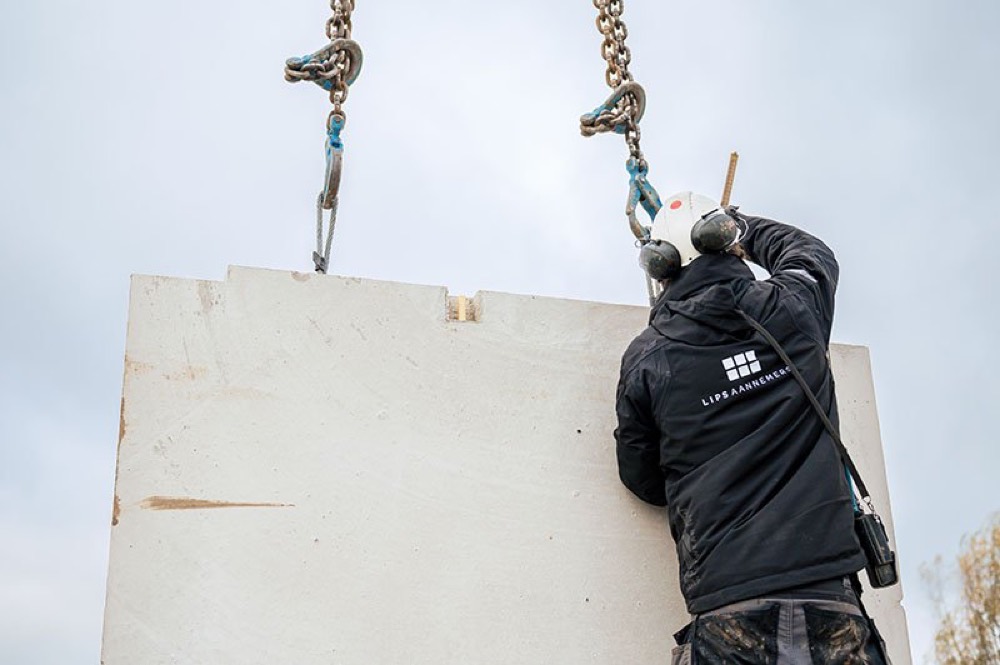 Timmerman van Lips Aannemers haakt een prefab wandelement aan de kraan